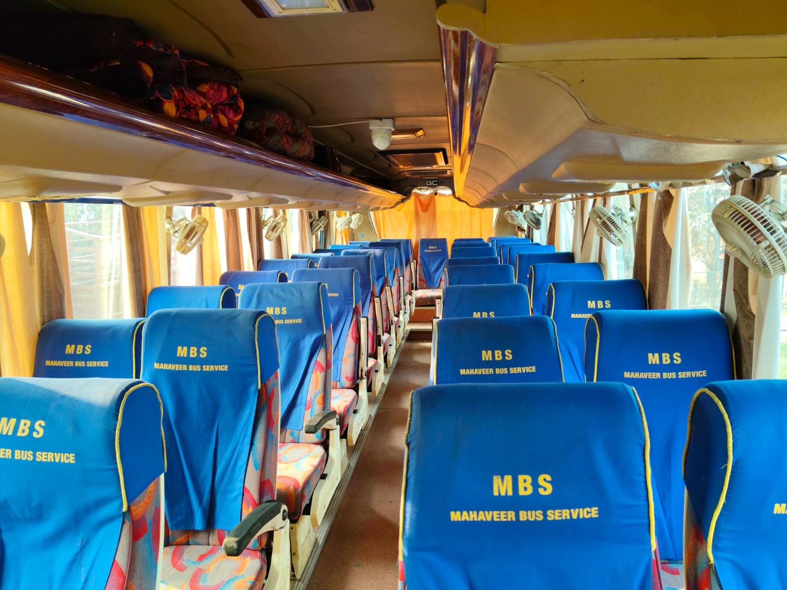 Spacious interior with MBS-branded seats, ceiling fans and overhead luggage racks